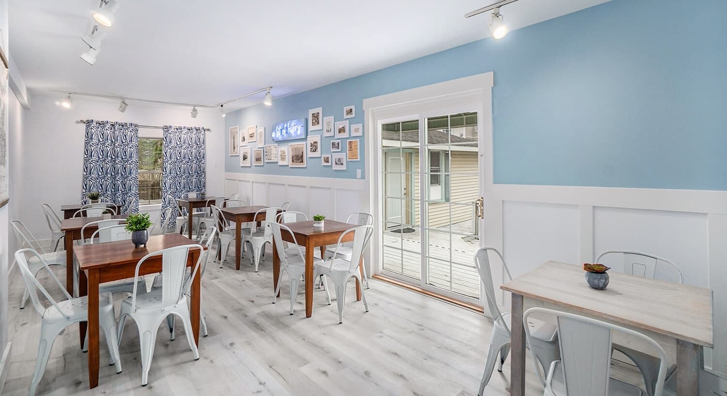 Bright café interior with wooden tables, white chairs, and blue accent walls.